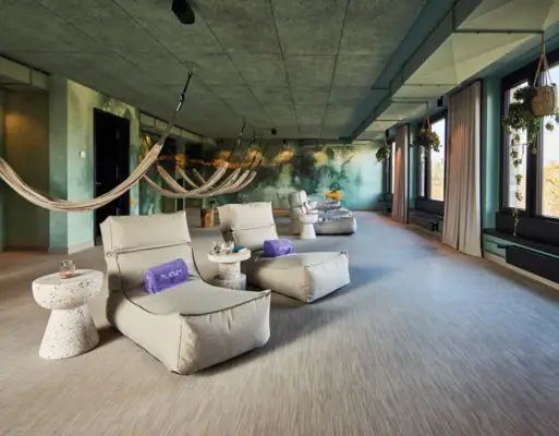 The relaxation room at the Urban Nature Hotel St. Peter-Ording with hammocks and comfortable armchairs.