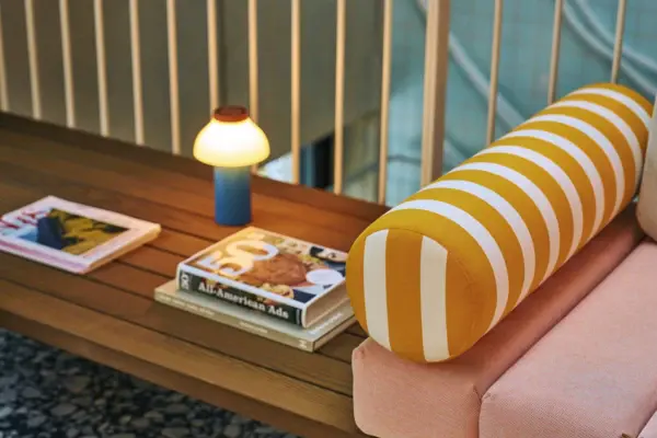 Close-up of a designer bench with striped roll, stylish table lamp and lifestyle magazines in the modern lounge area