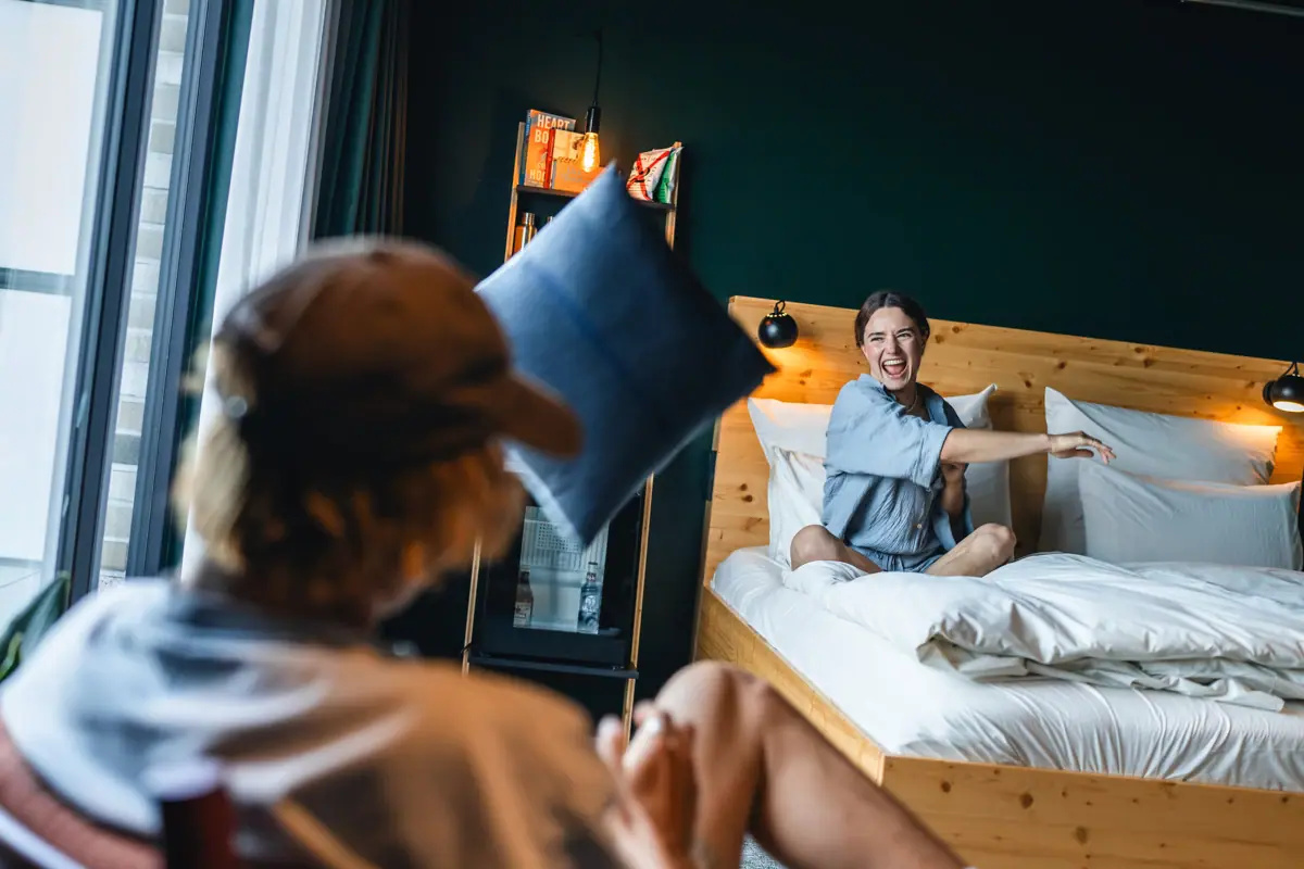 Accommodation in St. Peter-Ording A woman is sitting on a bed and throwing a pillow into the air.
