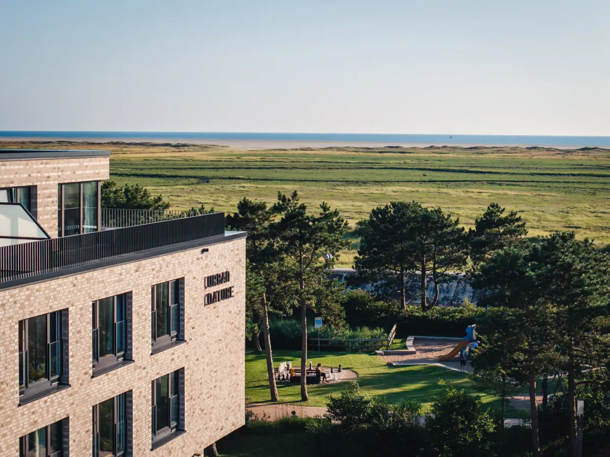 A building with trees and a body of water in the background.