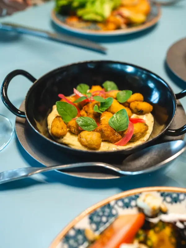 A dish is served in a small pan and garnished with basil.