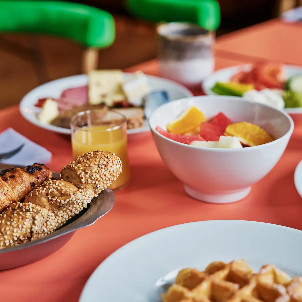 A breakfast table with dishes such as fruit, bread, eggs and orange juice.