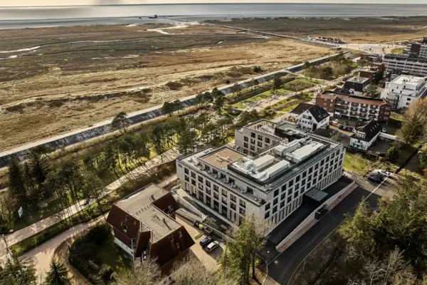 Urban Nature Hotel St. Peter-Ording A bird’s-eye view of the Urban Nature Hotel St. Peter-Ording next to the dyke, with the North Sea in the background.