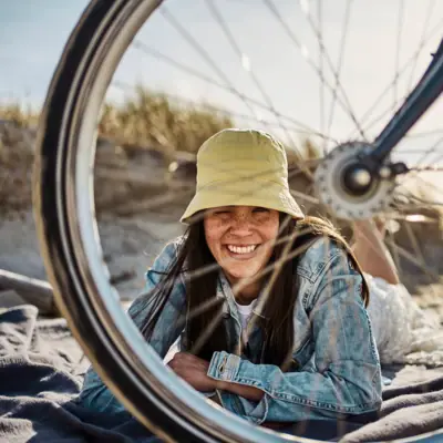 Summer holiday 2026 in St Peter-Ording A woman is lying on a blanket on the beach next to a bicycle tyre.