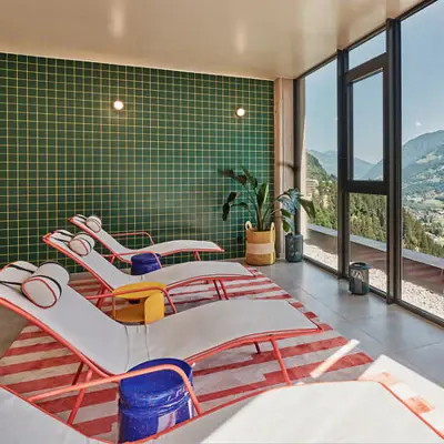 Bright relaxation room with stylish loungers, colorful furnishings and panoramic windows with a view of the mountains of Bad Gastein
