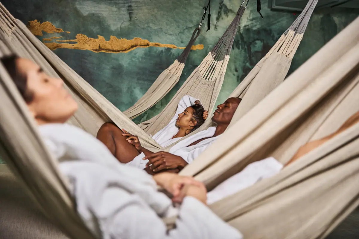 A group of people in white bathrobes in hammocks.