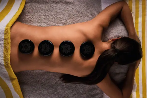 Hot-Stone-Massage Frau bei Hot-Stone-Massage mit schwarzen Lavasteinen auf dem Rücken