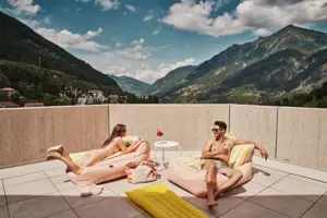 A man and a woman on a terrace with a mountain view.