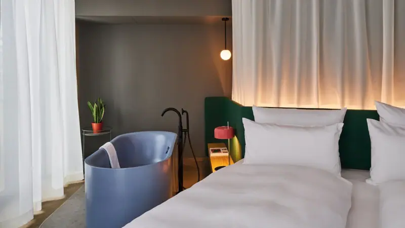 A bed with a bathtub and a lamp in a stylishly designed room.