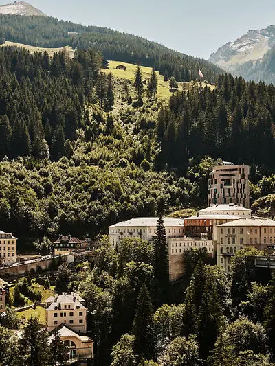 Historic buildings and modern hotel tower embedded in the green mountain landscape of Bad Gastein in summer
