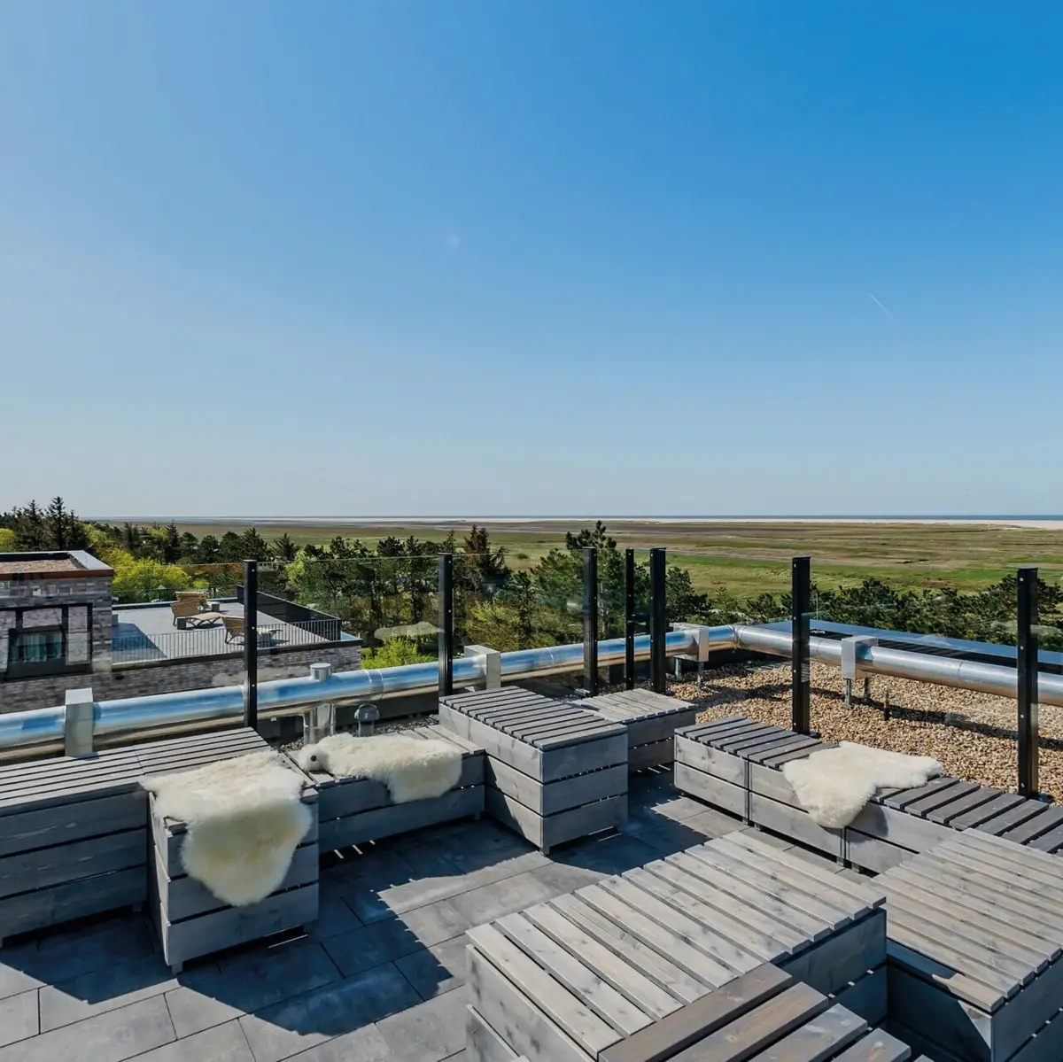 A roof terrace with wooden furniture and a great view over the salt marshes to the North Sea at St. Peter-Ording.