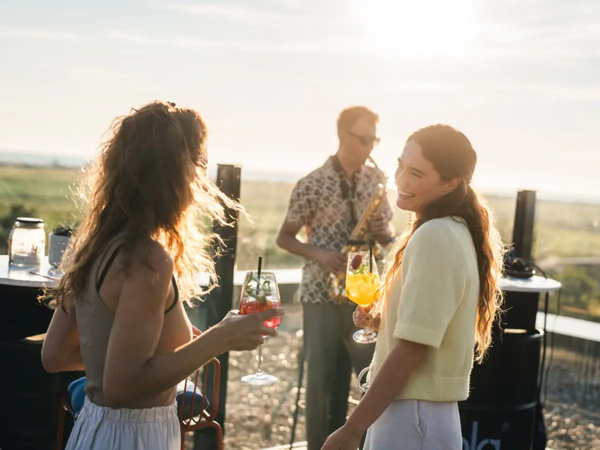 A group of women are holding drinks on a rooftop terrace.