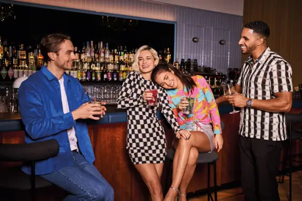 Drifters Hang Out im Urban Nature Hotel im Badeschloss in Bad Gastein Drei junge Erwachsene genießen bunte Cocktails an einer stilvollen Hotelbar