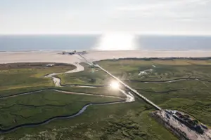 A path leading to a beach, with sky and water in the background.
