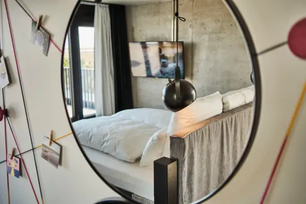 Rooms A mirror in a bedroom with a bed and bed linen.