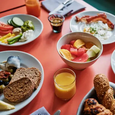 A breakfast table with dishes such as fruit, bread, eggs and orange juice.