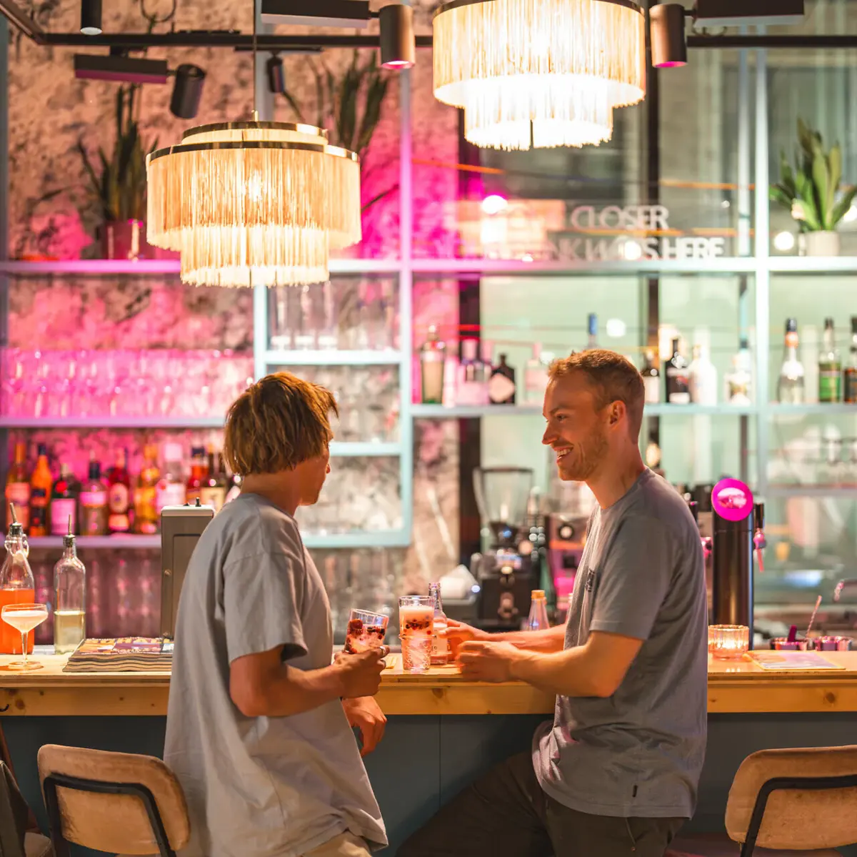 Two men are standing at the bar of Drifters Hang Out with drinks in their hands.
