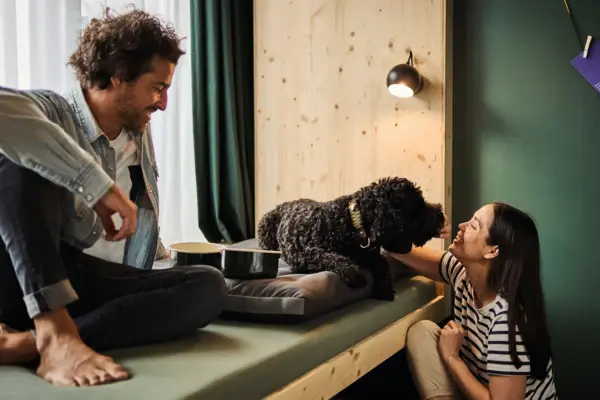 Urban Nature Dog Room A man and a woman are sitting in a room at the Urban Nature Hotel in St. Peter-Ording with a dog.