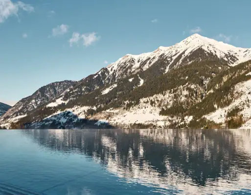 A body of water with snow-covered mountains under a blue sky.