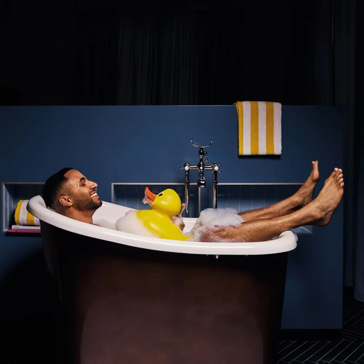 Bath A man is lying in a bath with a rubber duck.