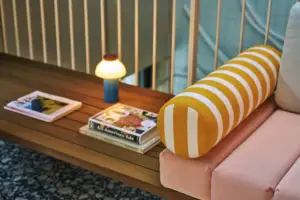 A table with a lamp and a yellow-and-white striped cushion.