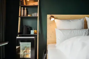A bed with a wooden headboard and a shelf with lighting in the background.