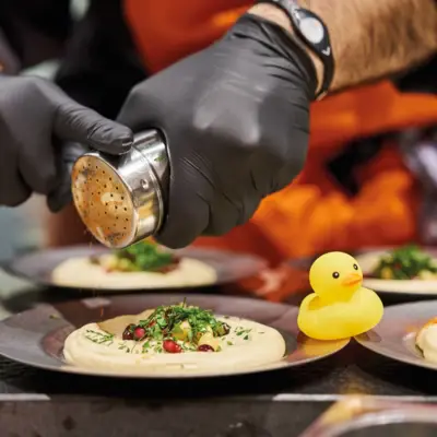 Several plates of hummus are served by a cook.