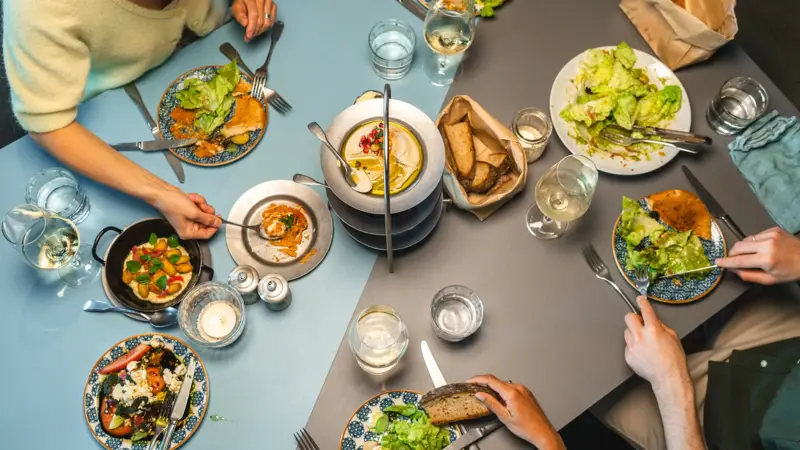 Group of people dining at a table laden with a variety of delicious dishes.