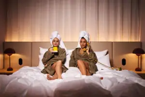 Two women in bathrobes on a bed.
