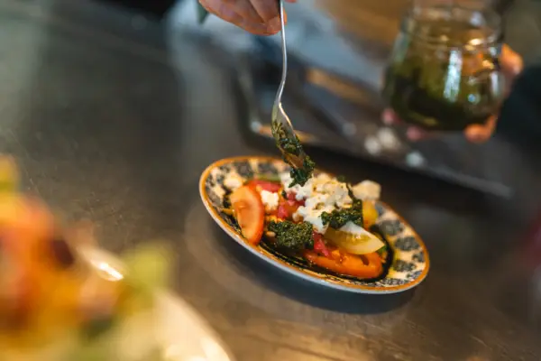 A chef prepares a dish with peaches and burrata on a kitchen worktop.