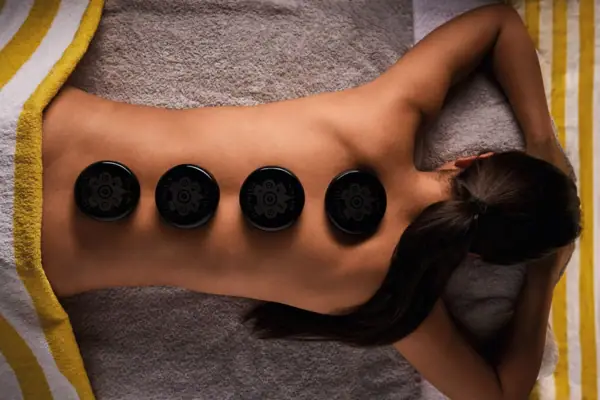 Woman having a hot stone massage with black lava stones on her back
