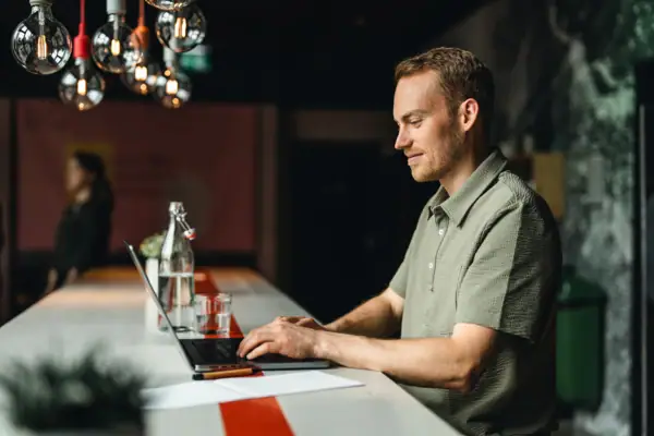 A man is sitting at a table using a laptop.