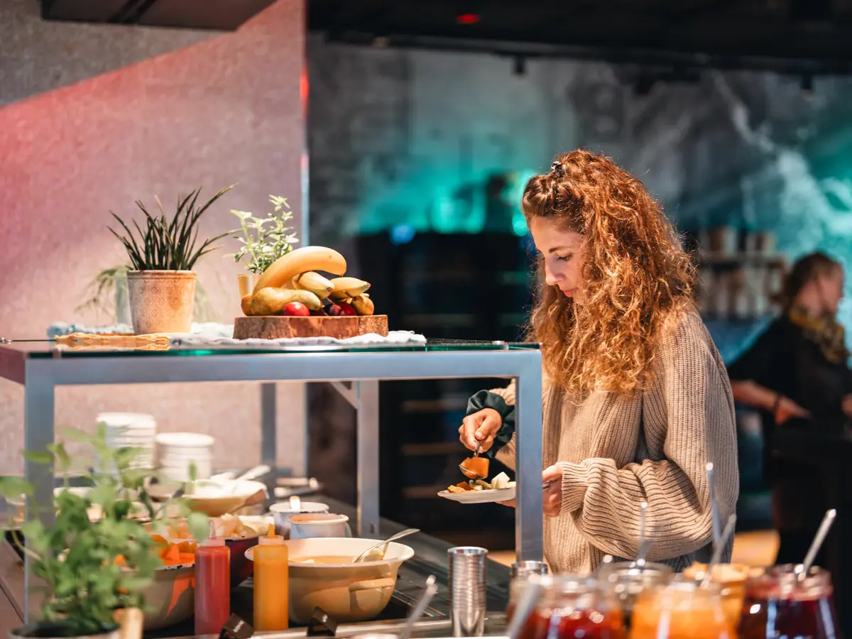 Breakfast buffet St. Peter-Ording A woman is standing at a breakfast buffet, putting food on her plate.
