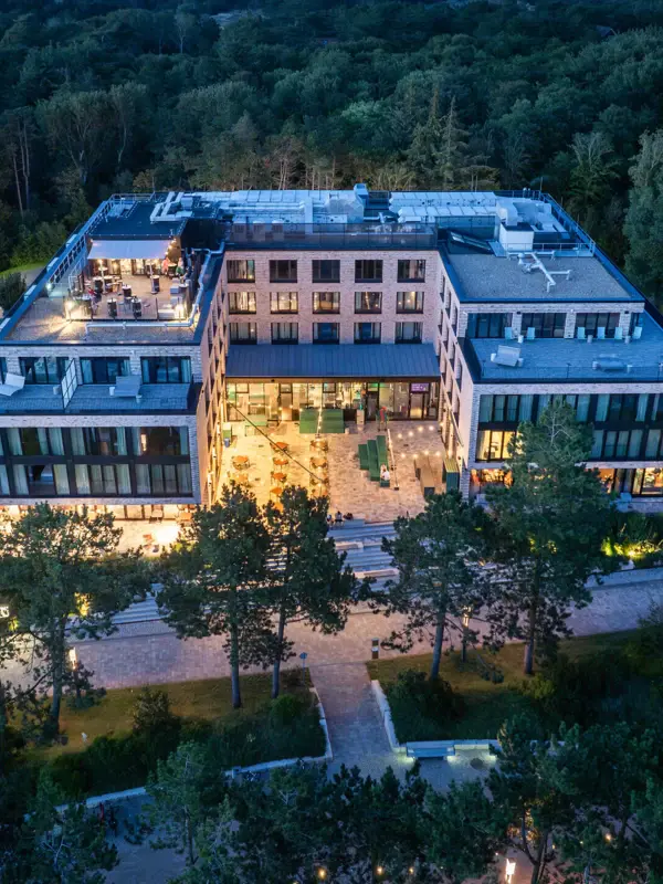 The Urban Nature Hotel in St. Peter-Ording photographed at night from above with trees in the background.