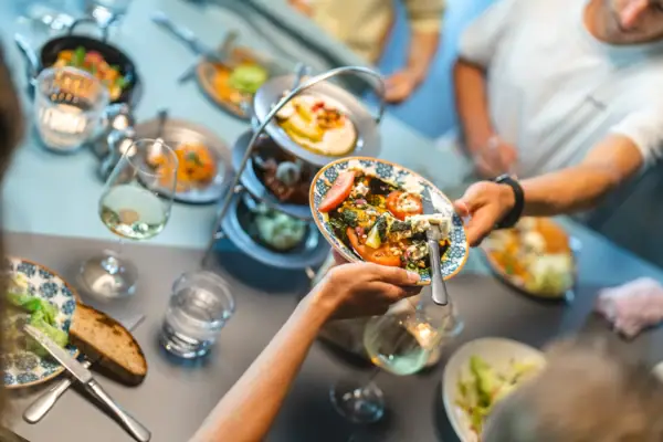 Auf einem Tisch im Auntie Clara Restaurant St.Peter-Ording stehen viele Teller und Vorspeisen in der Mitte, die sich eine Gruppe von Personen teilt.