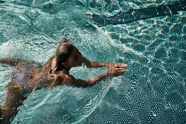 Woman swimming in a turquoise blue pool