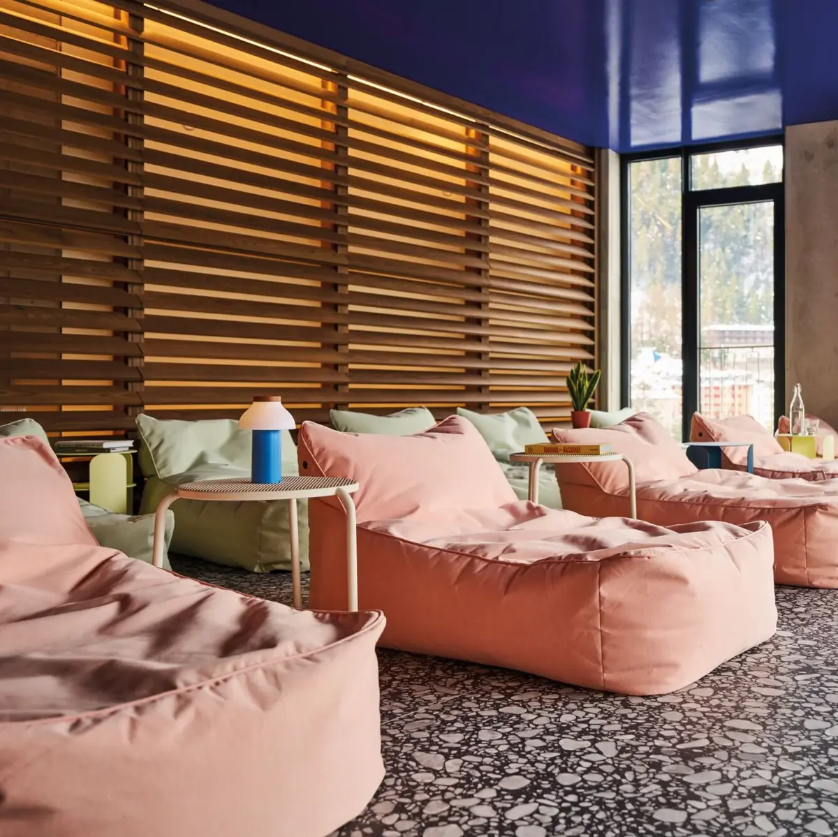 Modern relaxation room with cozy beanbags, stylish side tables and indirect lighting in front of a wooden slatted wall