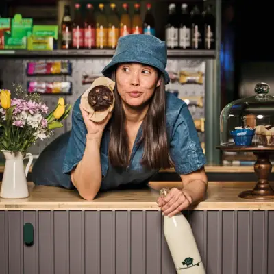 Woman in a hat leaning on the counter, holding a muffin at Urban Nature St. Peter-Ording.