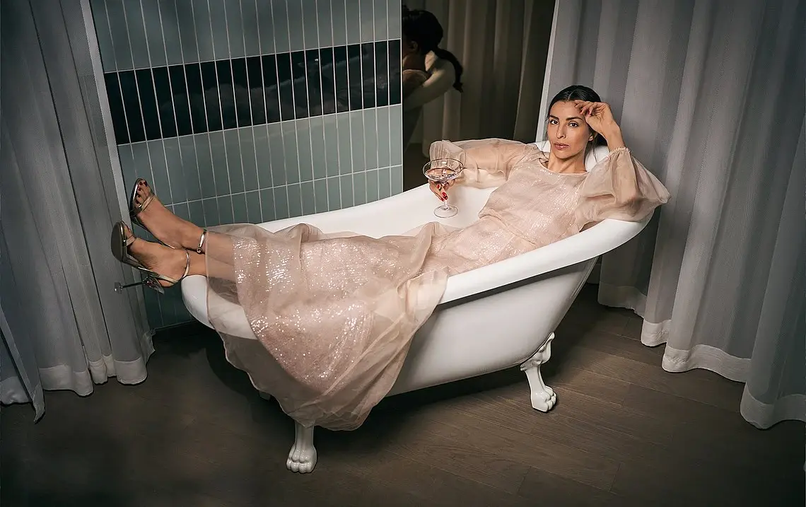 Woman in bathtub A woman lies in a dress in a free-standing bathtub, holding a drink in her hand.