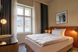 Bed with table and lamp in a room with a window.