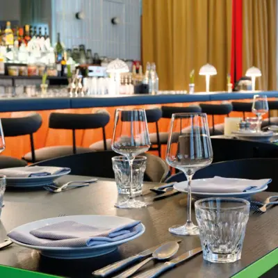 A set table in a restaurant with plates, glasses and napkins.