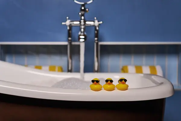 Drei Quitescheenten stehen auf dem Rand von einer Badewanne.