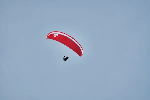 Eine Person beim Paragliden vor einem blauen Himmel.