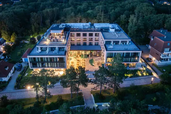 The Urban Nature Hotel St. Peter-Ording, with the surrounding trees, photographed from above at dusk.