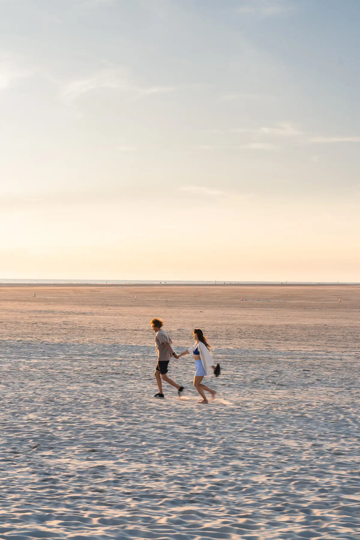 A man and a woman are holding hands on a beach.