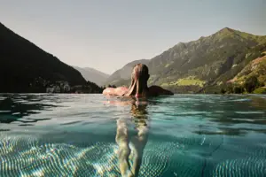 A woman swims in a pool with mountains in the background.