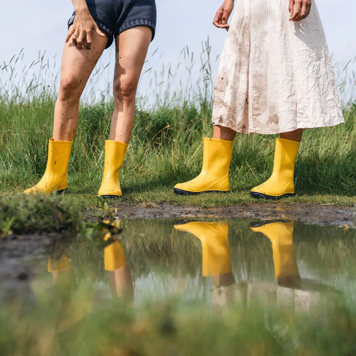 Rubber boots Two women wear yellow boots and stand in a puddle.