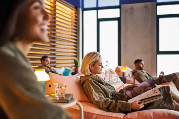 Several people lie in comfortable armchairs in a relaxation area and wear bathrobes.