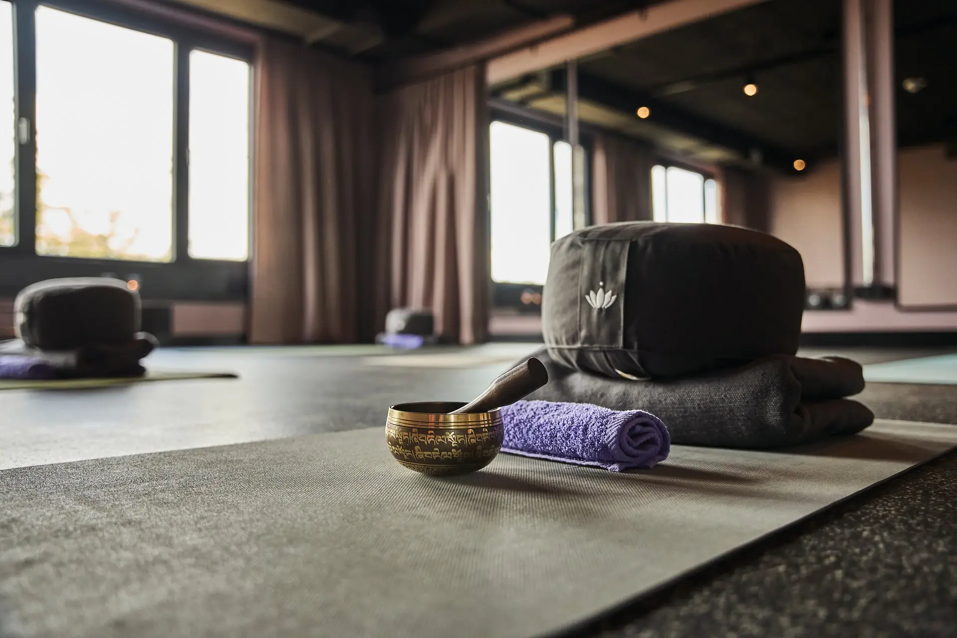 Yogaroom Urban Nature St. Peter-Ording Several yoga mats are available in a yoga room at the Urban Nature Hotel St. Peter-Ording, along with a sound bowl, a towel, a seat cushion, and a blanket.