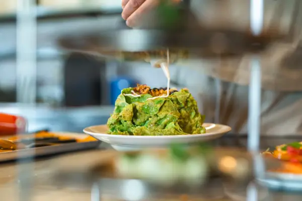 A chef prepares a green dish on a kitchen worktop.